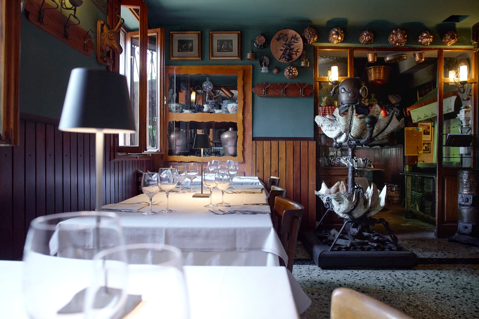 Sala d'epoca con tavoli apparecchiati, lampada nera e specchio dorato