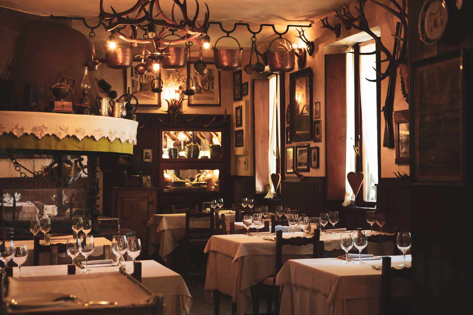 Sala interna della Trattoria Alla Vedova con corna di cervo, rame appeso e tavoli apparecchiati